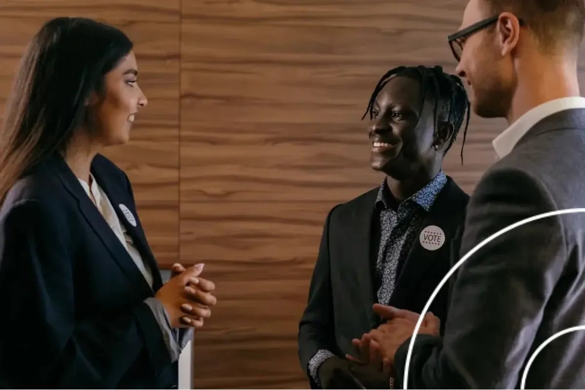Three professionals in business attire discussing during an association engagement platform networking event at office.
