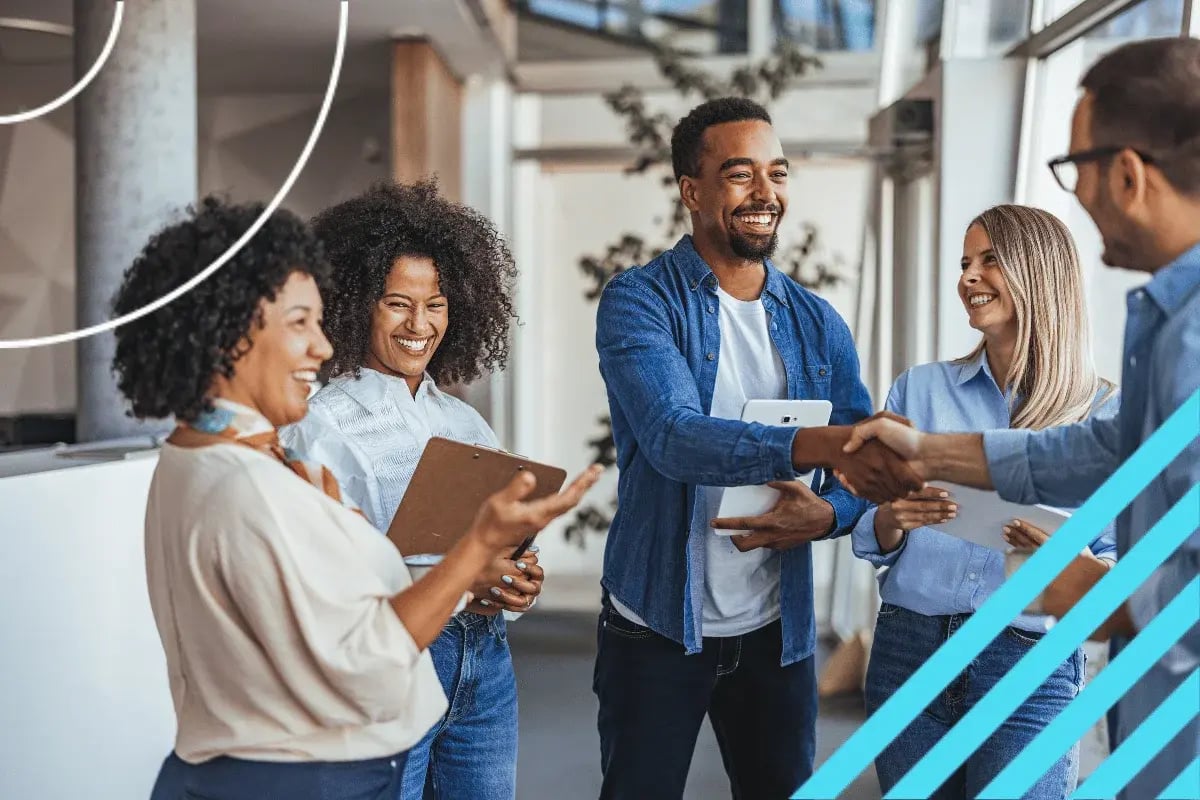 Diverse professionals smiling during a handshake in a modern office, showcasing teamwork and business collaboration.