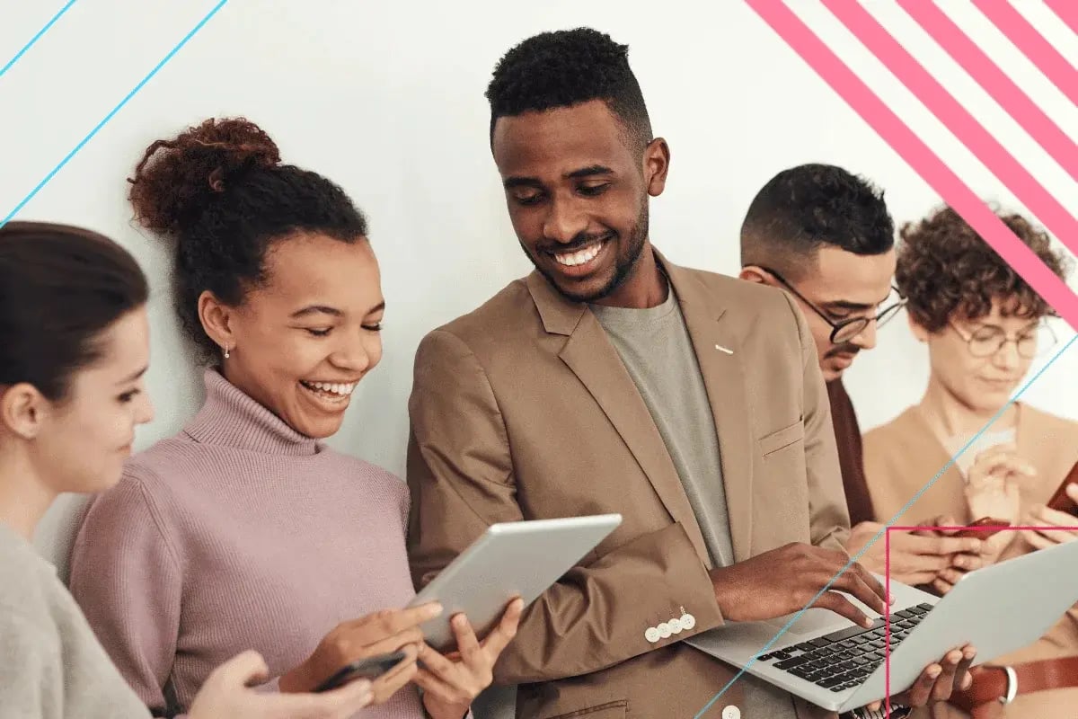 A diverse group of five people smiling and interacting with digital devices, including tablets and laptops.