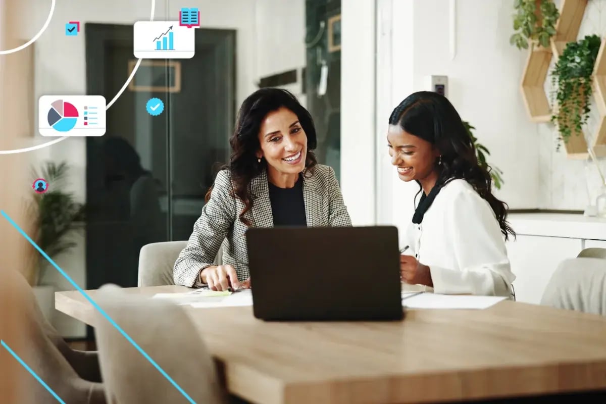 Two women collaborate over a laptop at a bright office table, surrounded by business analytics icons, conveying teamwork, trust, and success.