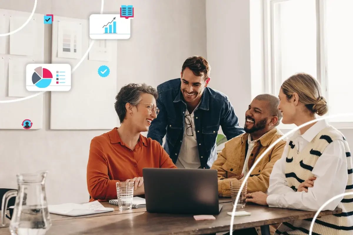 A group of four people smiling and collaborating around a laptop in a bright office.