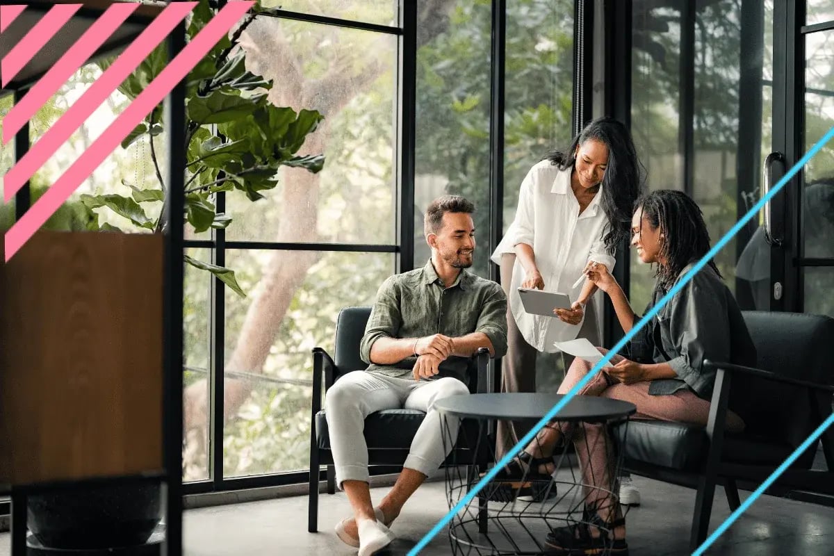 Team members reviewing tablet content together in a relaxed office lounge setting.