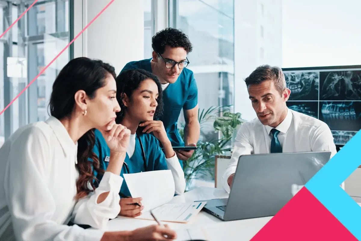 A diverse group of three medical professionals and a businessman discuss over a laptop in a modern office, appearing focused and collaborative.